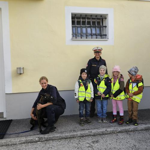 Volkschulkinder mit zwei Poluistinnen und dem Polizeihund vor der Polizeistelle 