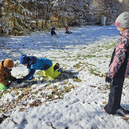 Zwei Schüler spielen im Schnee, eine weiter Schülerin beobachtet sie 