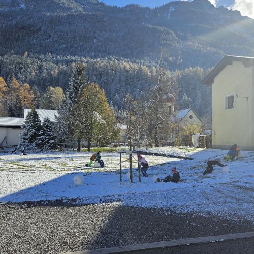 Schüler rollen Schneekugeln auf einer Wiese 