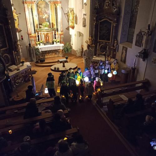 Auf dem Bild sind Kinder mit Laternen in der Hand in der Kirche zu sehen