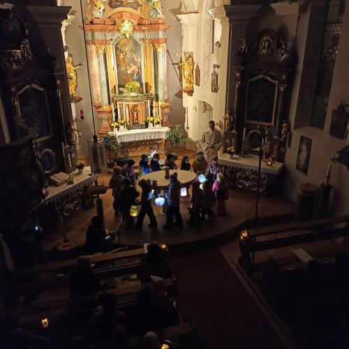 Auf dem Bild sind Kinder mit Laternen in der Hand in der Kirche zu sehen