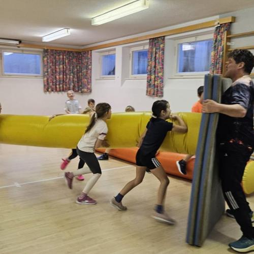 Die Mädchen versuchen mit der Hüpfnudel Matten umzustoßen 