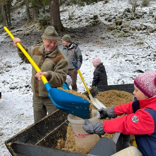 Jäger teilt den Kindern Futter für die Wildtiere aus