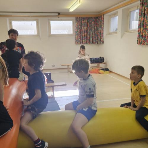 Drei Kinder sitze auf der Luftnudel und ein Kind krabbelt über eine Nudel 