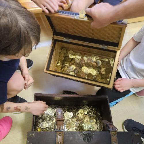 Kinder schauen in zwei Schatztruhen mit Spielmünzen