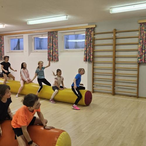 Schüler sitzen auf der Rollnudel und Andi macht Bewegungen vor 