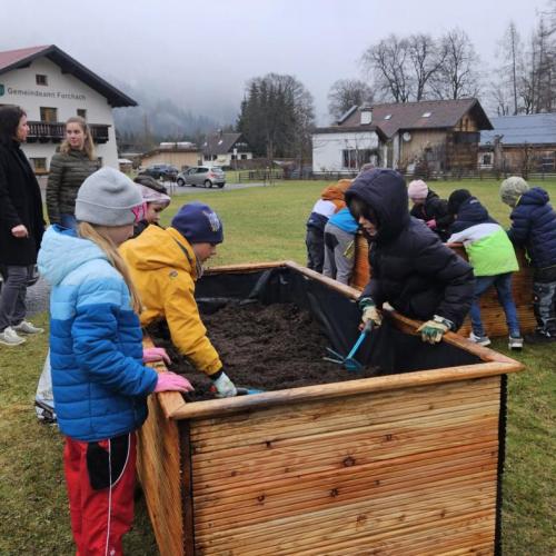Schüler füllen die Hochbeete mit Erde 