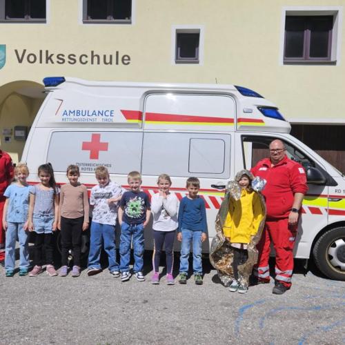 Die Schüler stehen mit den Sanitätern vor dem Rettungsauto 