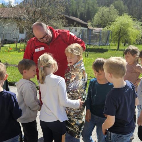 Bertram wickelt einen Schüler in eine Rettungsdecke, die anderen schauen zu