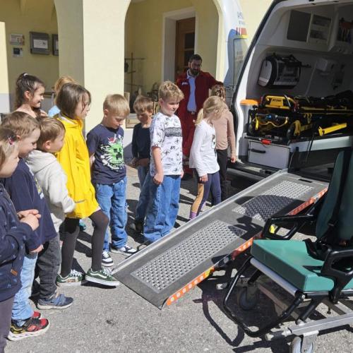 Schüler stehen vor dem Rettungsauto und der Sanitäter zeigt den Rollstuhl