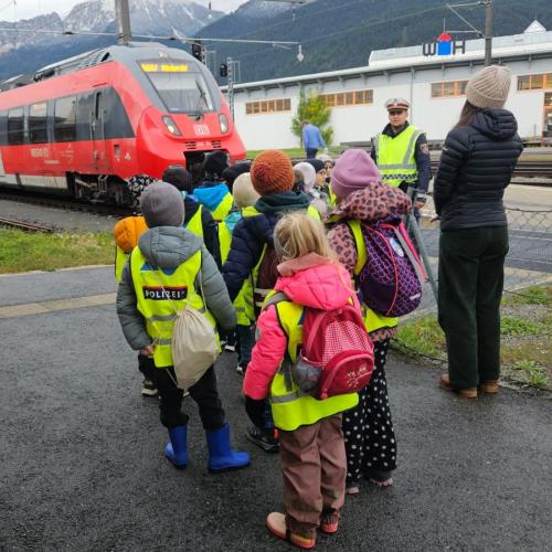 Ein Polizist und mehrerer Schüler/innen stehen vor einem Zug
