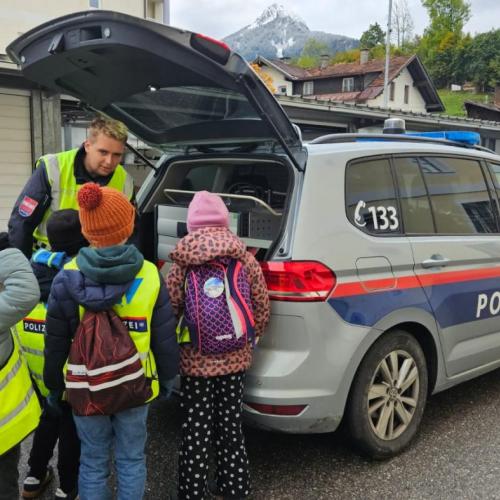 Ein Polizist zeigt den Schülern das Polizeiauto