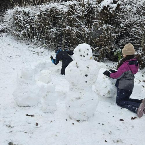 Zwei Schüler bauen einen Schneemann