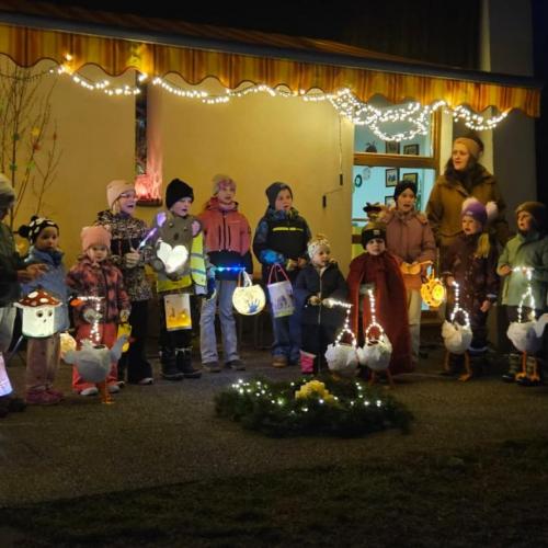 Kindergartenkinder und Volksschulkinder stehen mit ihren Laternen im Halbkreis