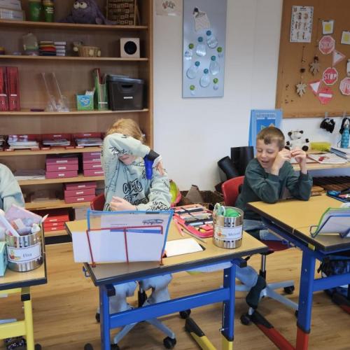 Drei Kinder sitzen mit geschlossenen Augen bei ihrem Tisch