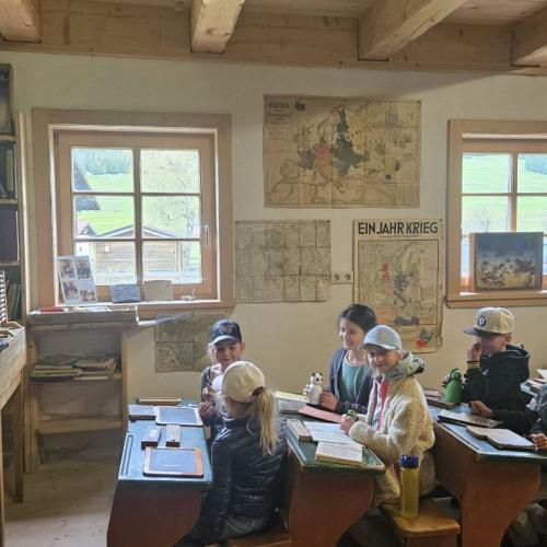 Schüler sitzen im Museum auf alten Schulbänken