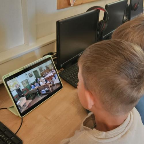 Kinder schauen auf einem Tablet eine Video über  wie war die Schule früher 