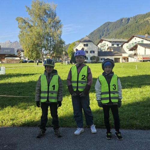 3 Viertklässler stehen mit der Sicherheitsweste vor einem Laubbaum