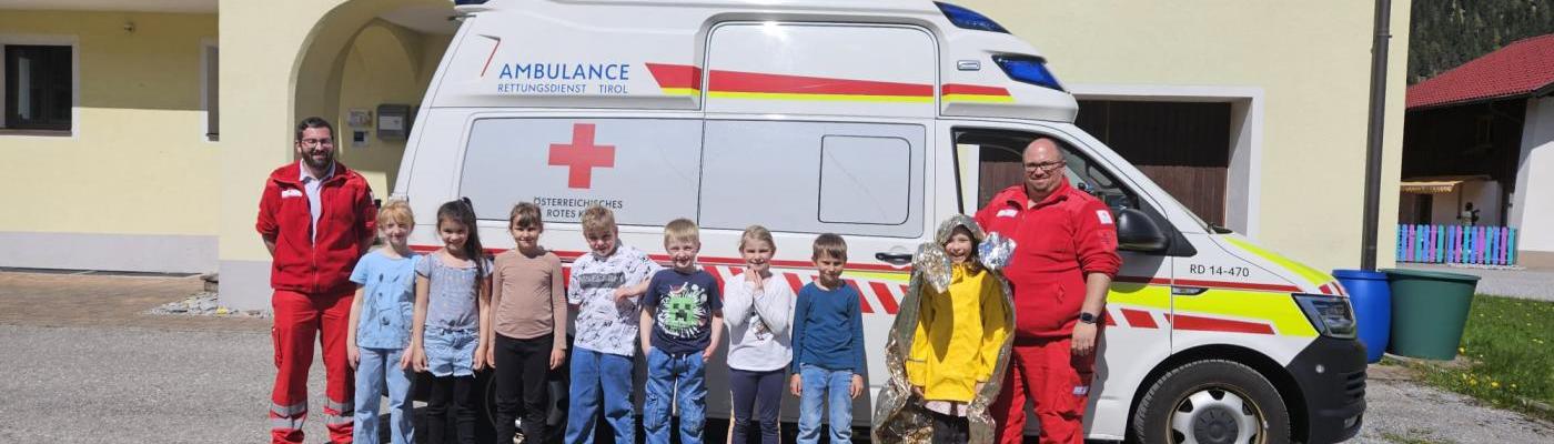 Die Schüler stehen mit den Sanitätern vor dem Rettungsauto 