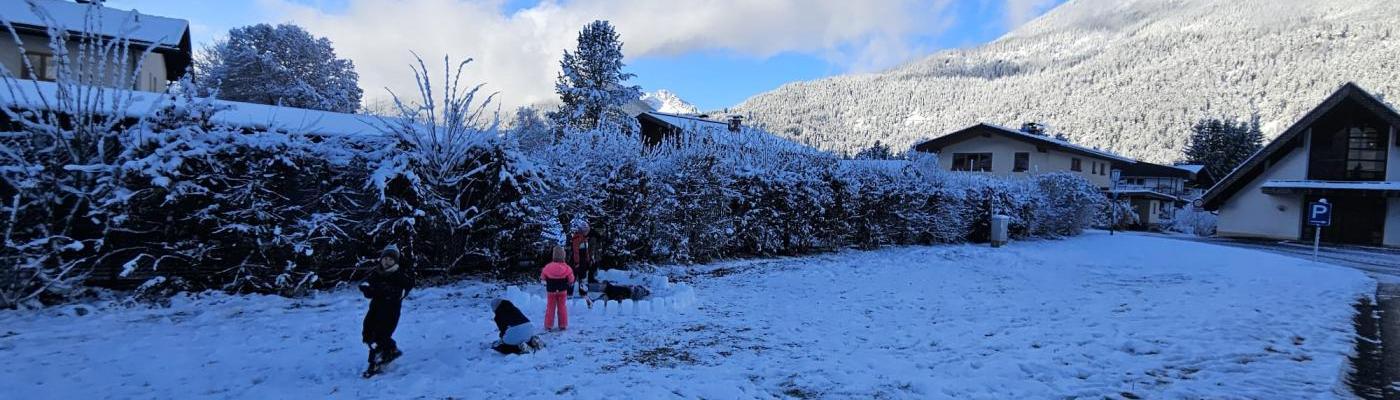 Im Hintergrund verschneite Landschaft und vorne spielen Kinder im Schnee
