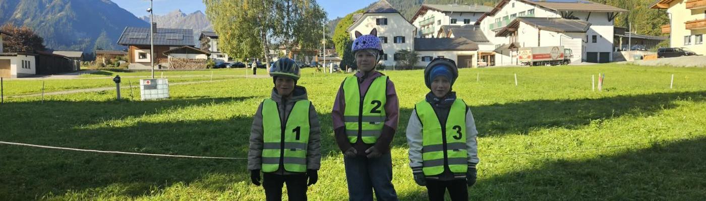 3 Viertklässler stehen mit der Sicherheitsweste vor einem Laubbaum