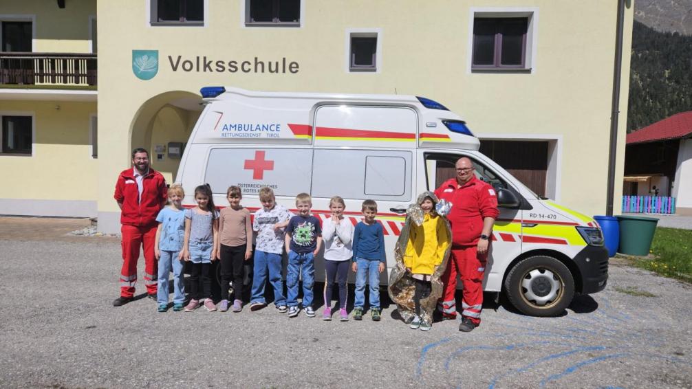 Die Schüler stehen mit den Sanitätern vor dem Rettungsauto 