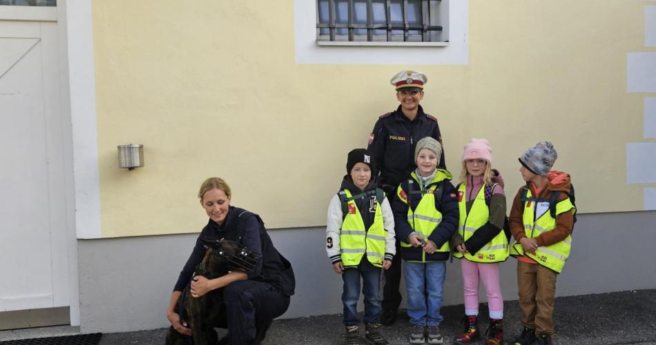 Vier Schüler stehen mit zwei Polizistinnen und einem Polizeihund vor der Polizeistation
