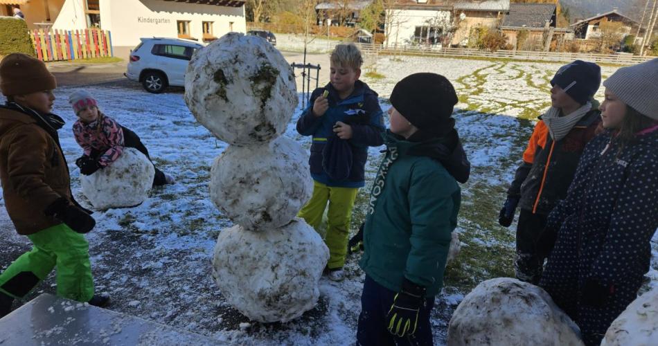 Schüler stehen um einen Schneemann