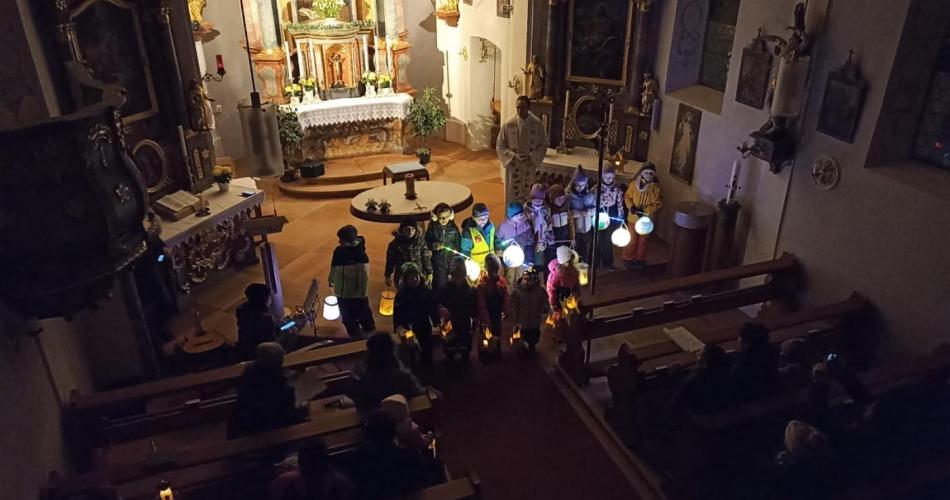 Auf dem Bild sind Kinder mit Laternen in der Hand in der Kirche zu sehen