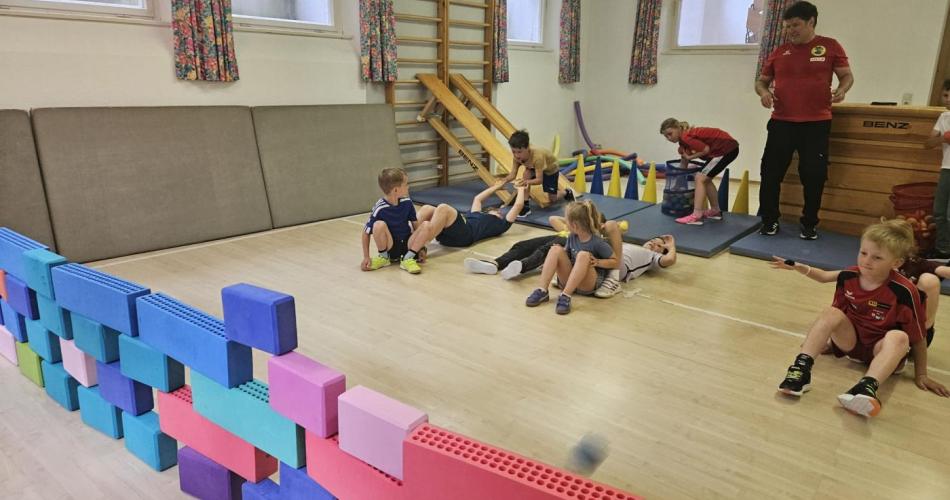 Kinder versuchen mit Bällen eine Mauer umzuwerfen