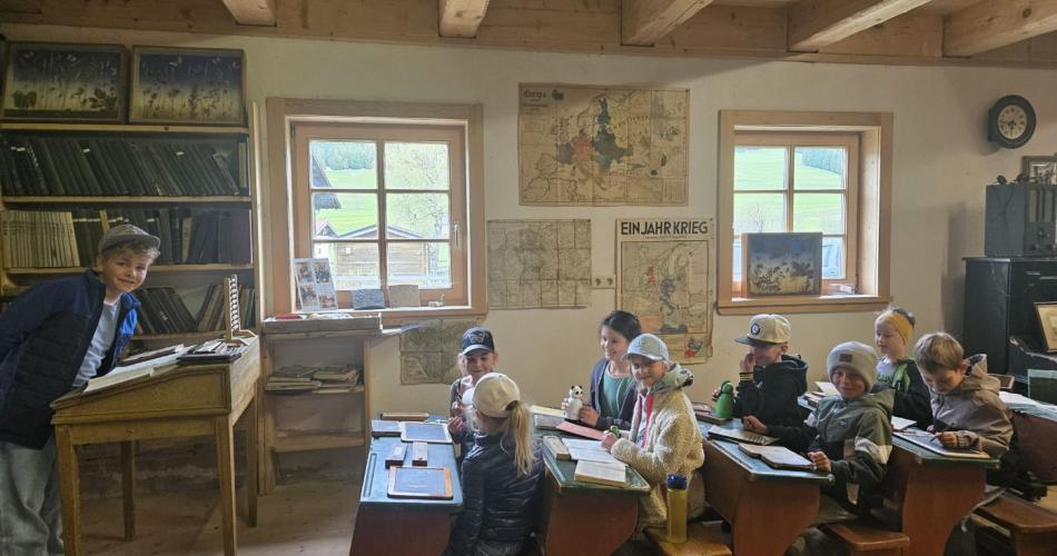 Schüler sitzen im Museum auf alten Schulbänken